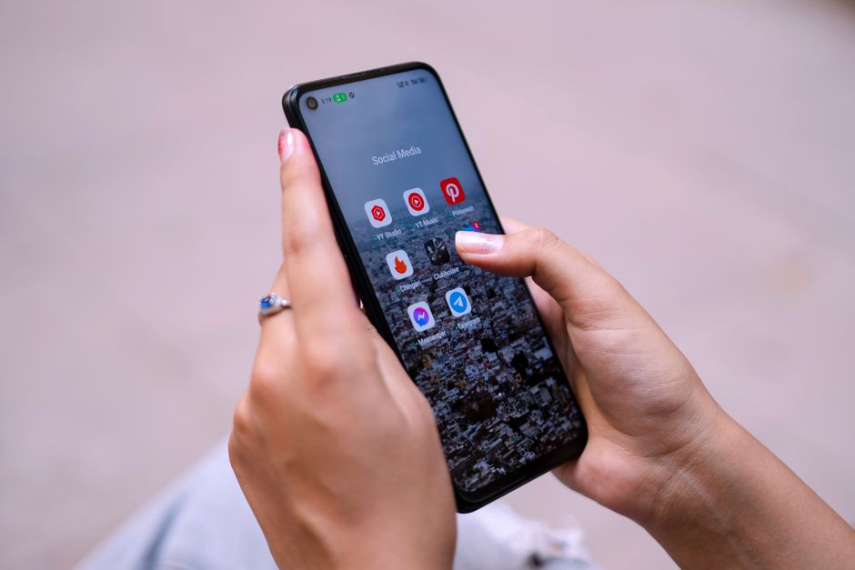 Close-up of hands holding a smartphone displaying social media apps, emphasizing digital connectivity.